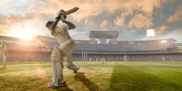 A close up image of a professional cricketer playing in batsman position wearing cricket whites and safety helmet, having just hit a ball during a cricket match in an outdoor stadium full of spectators. The action occurs under an evening sky at sunset. Stadium is fake, created from photographic and CG elements.