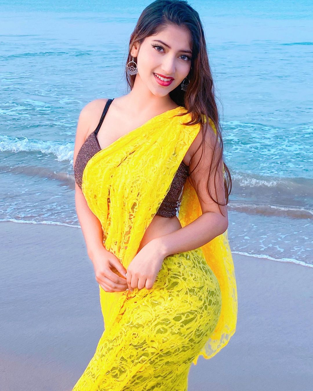at the beach in yellow saree
